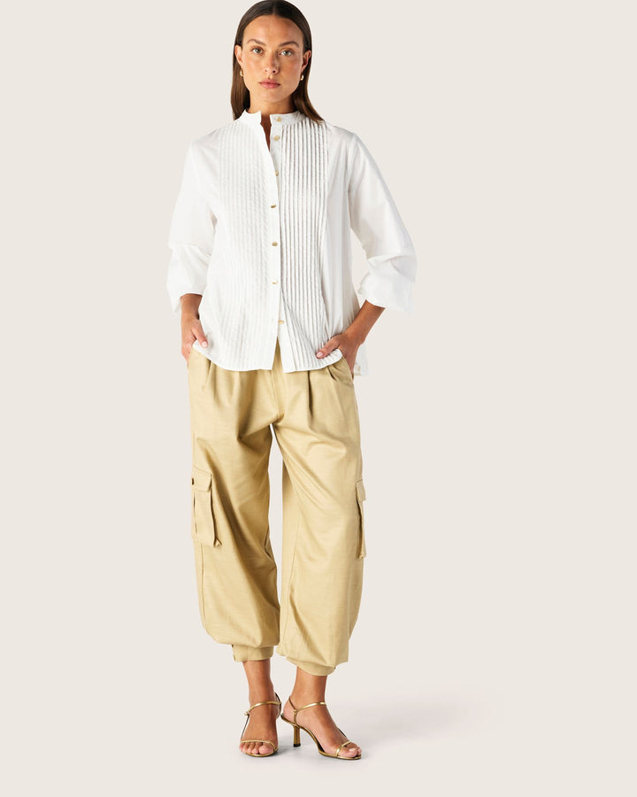 Woman wearing a white shirt and beige pants on a plain background